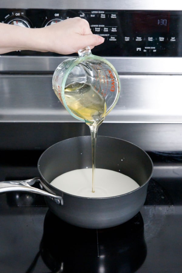 Pouring candied orange sugar syrup into saucepan with milk and cream.