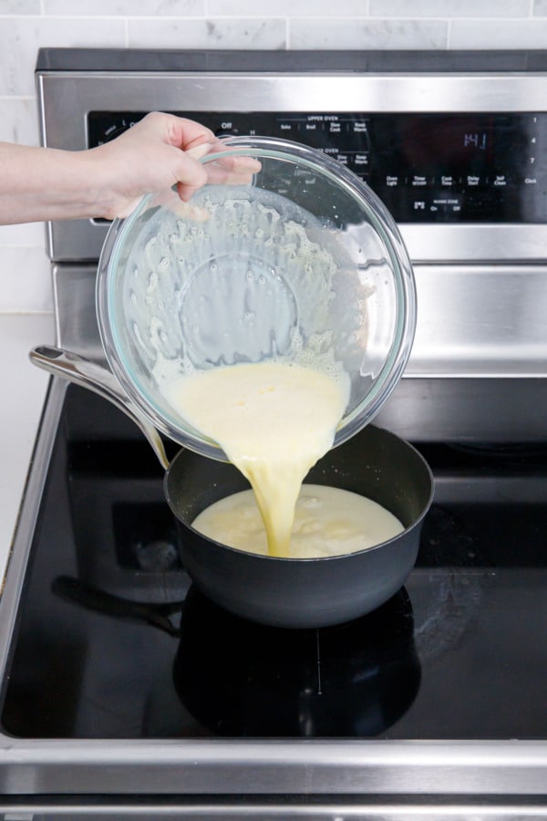 Pouring tempered egg yolk mixture back into saucepan with the rest of the milk.
