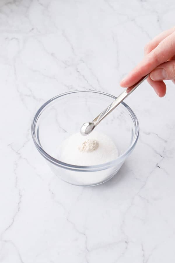 Whisking powdered guar gum with 1 tablespoon sugar in a small glass bowl.
