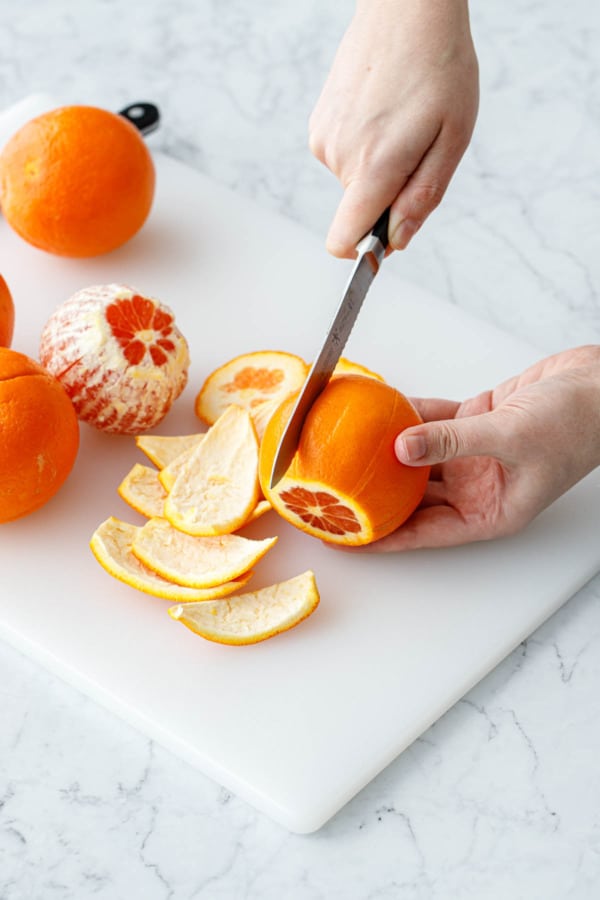 Scoring the peel of an orange 1/4-inch deep around the circumference of the orange.