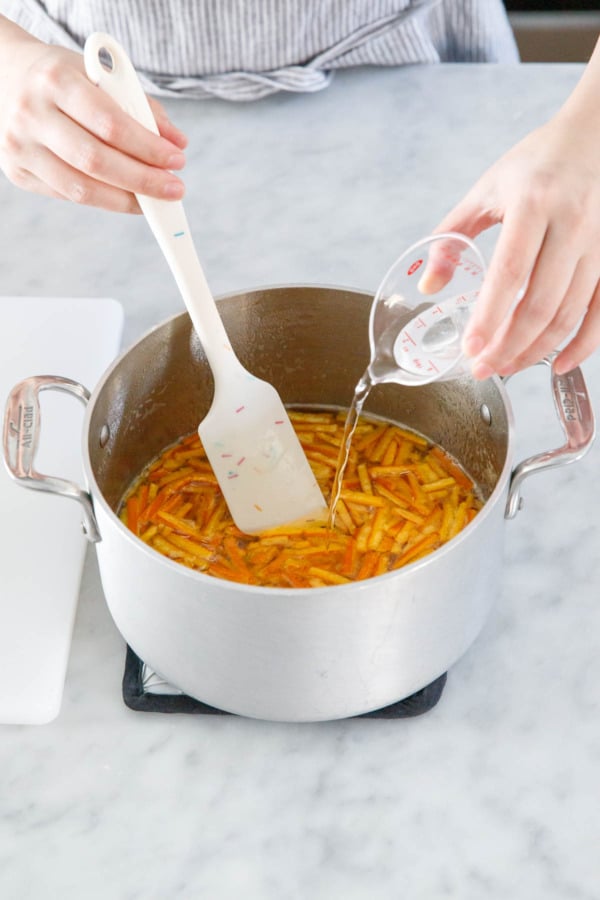 After removing pan from the stovetop, pouring citric acid dissolved in water into the candied orange peel syrup.
