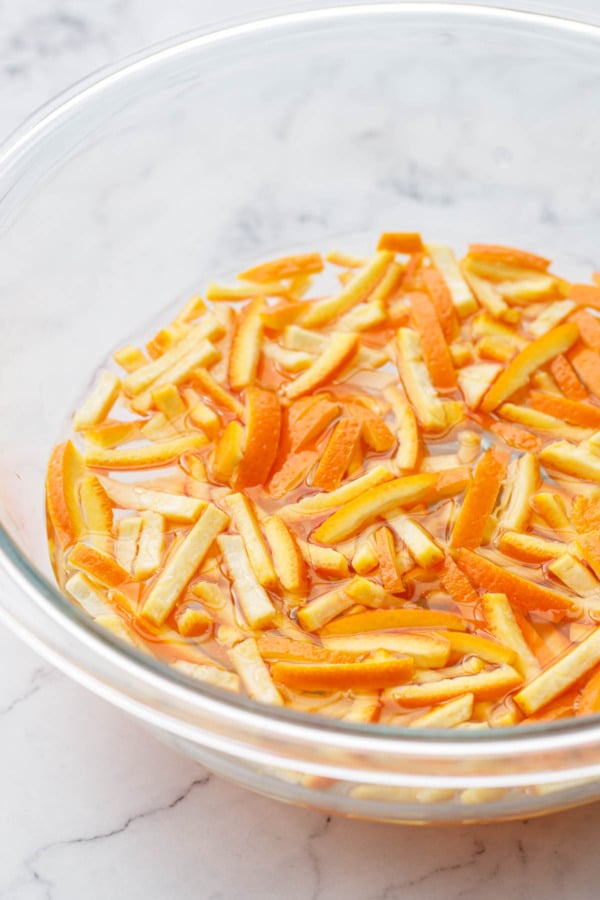 Soaking strips of cut orange peel in a bowl of cold water.
