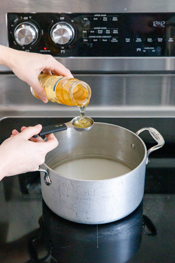Measuring honey into a saucepan along with sugar and water.