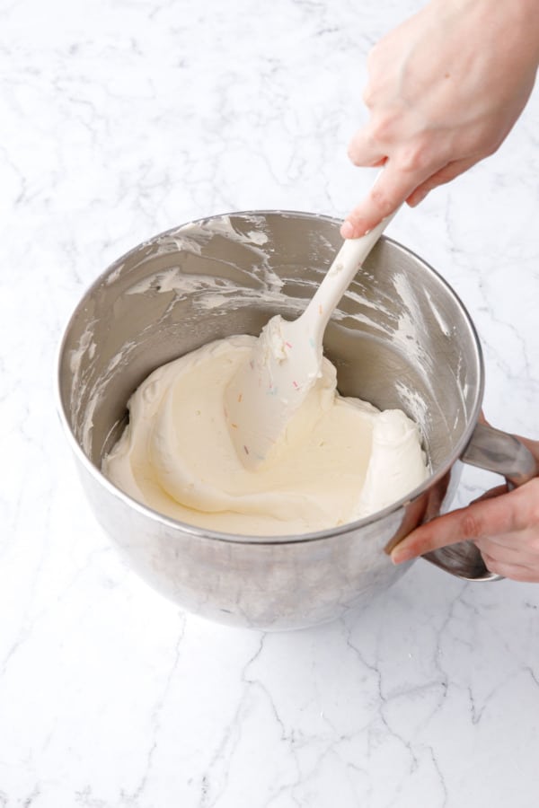 Spatula running through freshly whipped buttercream to show the light and fluffy texture.