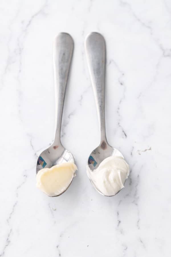 Two spoons, one with plain butter and one with fully creamed butter which has a noticeably whiter color and fluffier texture.