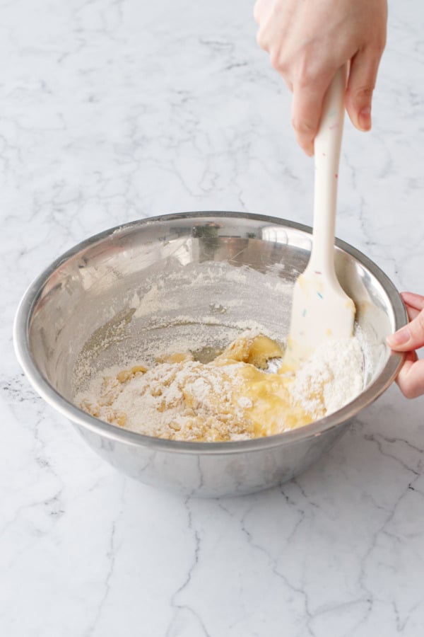Stirring melted butter into dry ingredients with a silicone spatula.