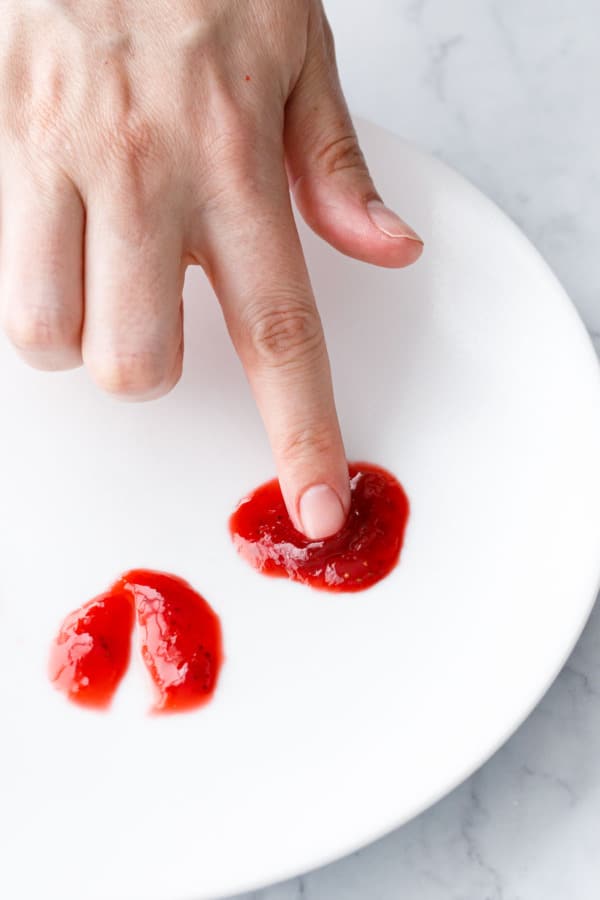 Testing the gel of the jam by pushing a finger through a chilled dollop of jam on a plate, it should wrinkle up in front of your finger.
