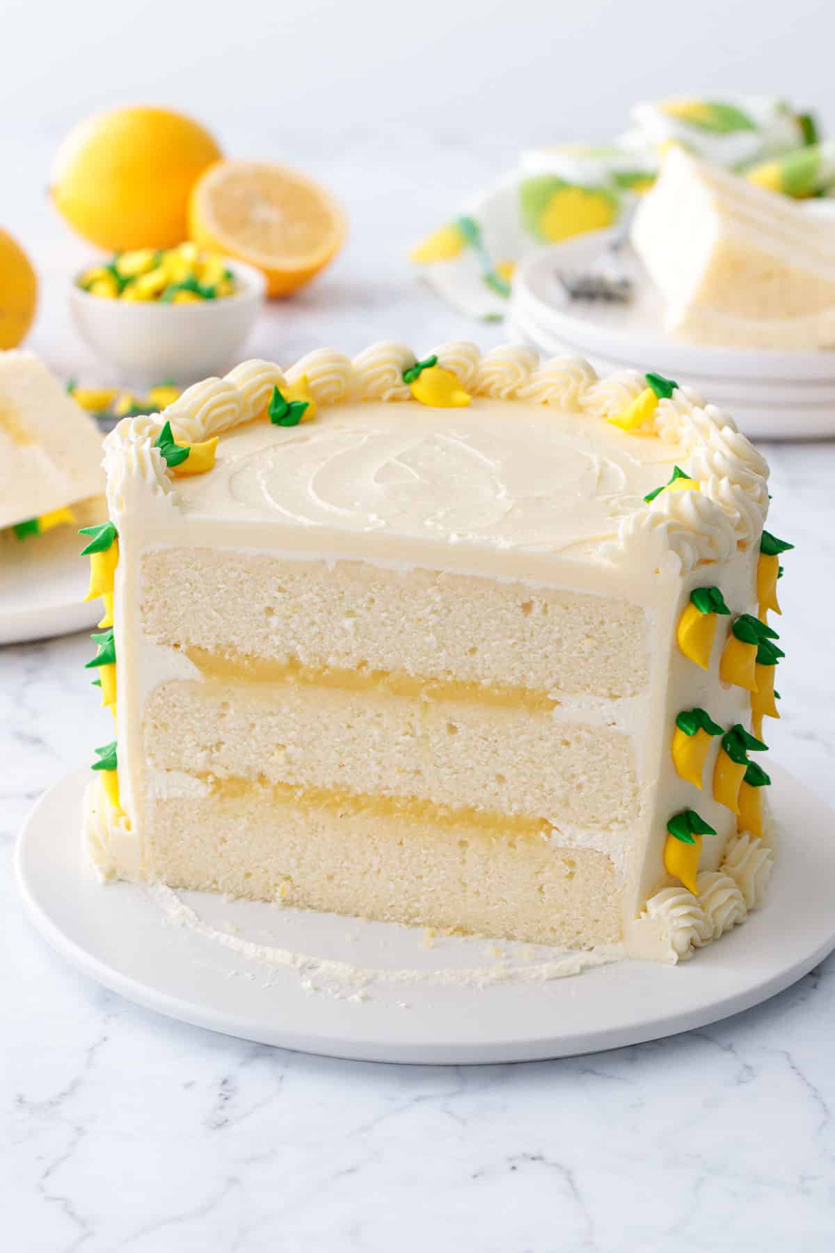 Triple Lemon Layer Cake with the front sliced off to show the three layers of frosting and lemon curd inside.