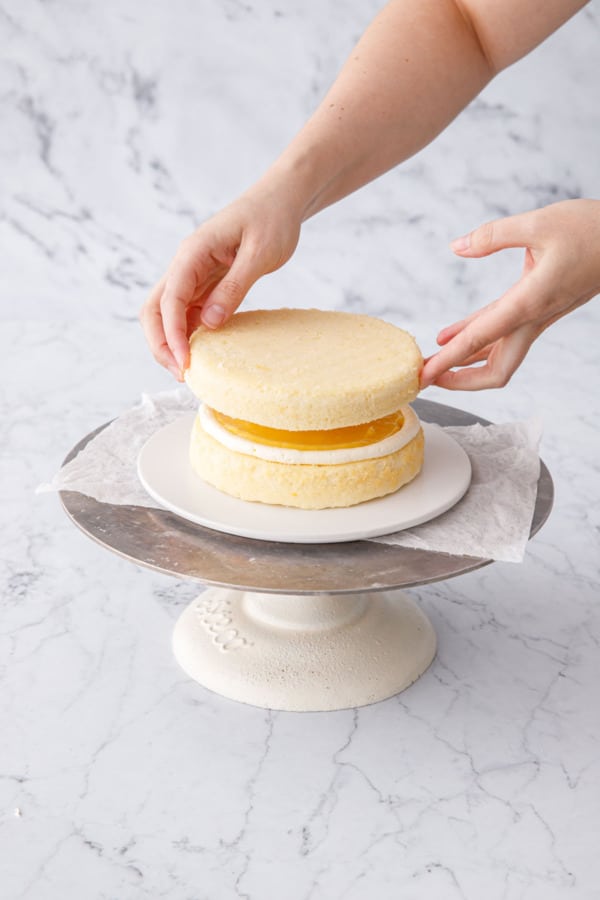 Adding the next cake layer of the Triple Lemon Layer Cake.