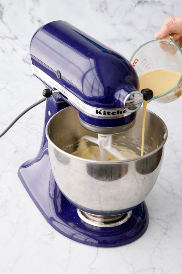 Adding remaining wet ingredients (milk mixed with eggs and vanilla) with the mixer running on low.