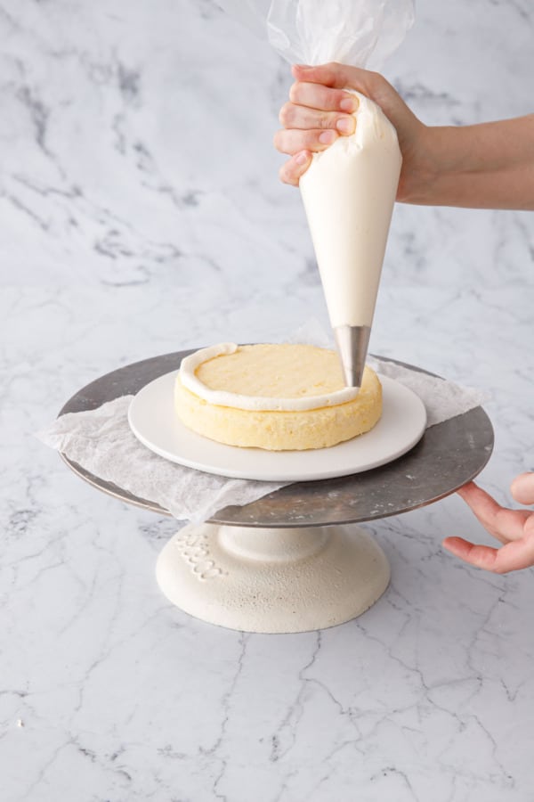 Piping a border of buttercream around the bottom cake layer (this will keep the curd from leaking out).