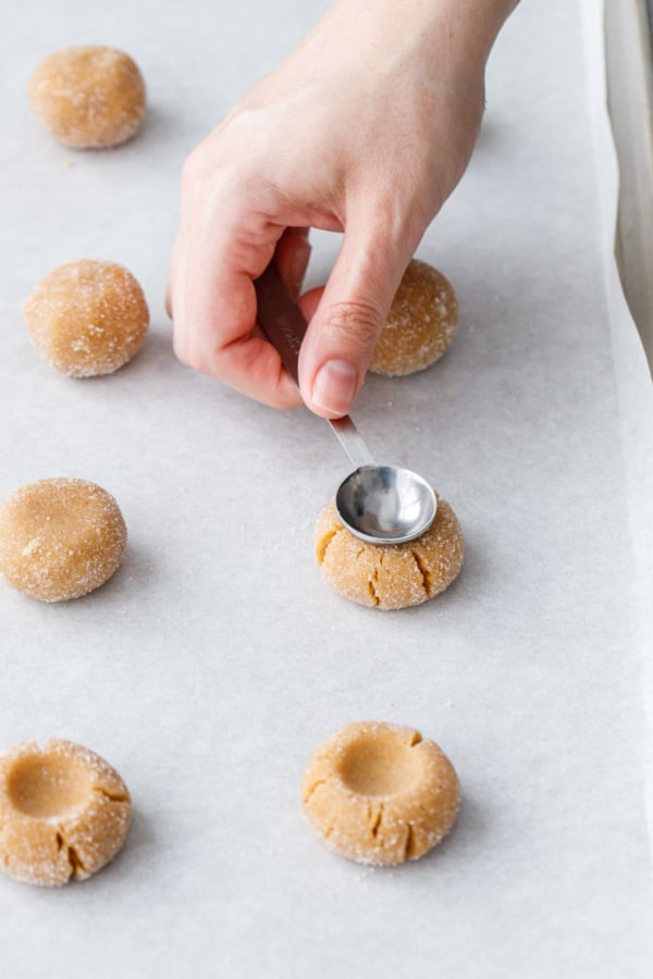 Using the back of a half-teaspoon measurer to lightly intent the tops of the unbaked dough balls.