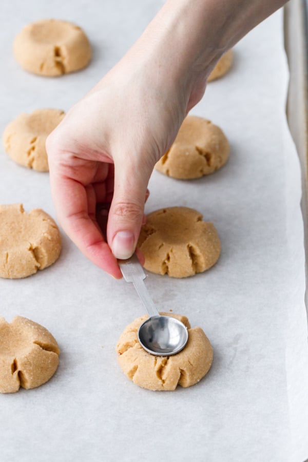 After partially baking, use the same measuring spoon to re-indent the thumbprints in the tops of the cookies.