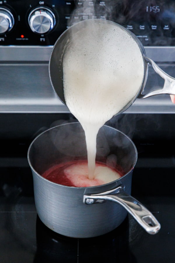 Pouring foamy pectin mixture into saucepan with raspberry puree.