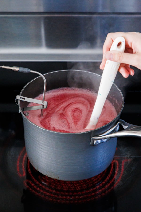 Simmering raspberry mixture on the stovetop in a medium saucepan.