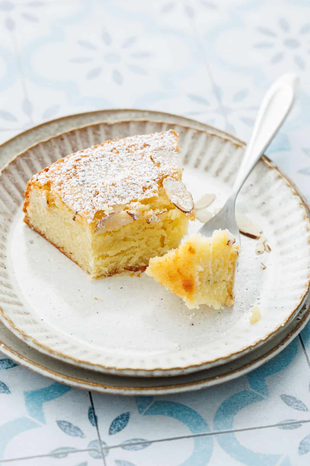 Slice of Flourless Almond Flour Cake on a plate with a biteful on a fork to show the soft, velvety texture of the crumb.