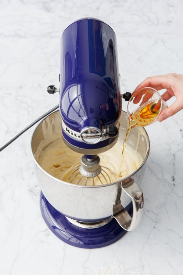 Pouring in Grand Marnier into mixing bowl with nearly-mixed cake batter.