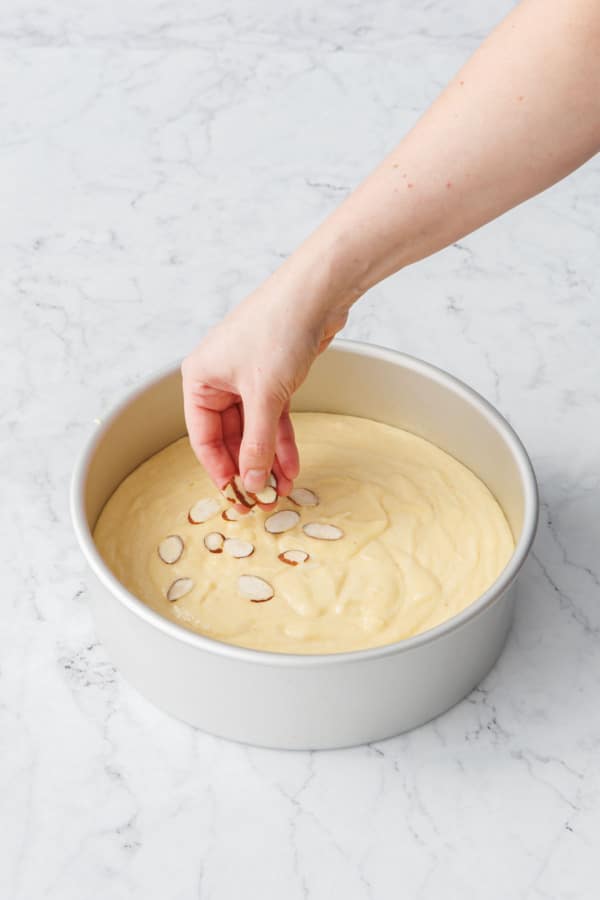 Sprinkling sliced almonds on top of the unbaked cake.