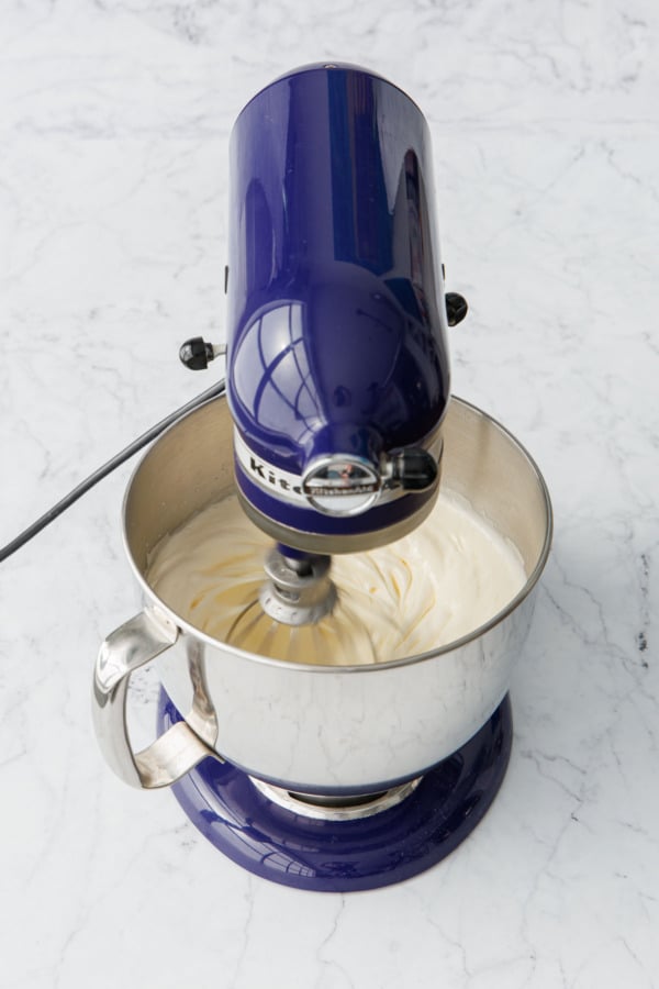 Whipping whole eggs and sugar with an electric mixer until very light in color, thick, and fluffy.