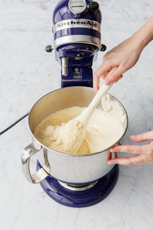 Rubber spatula gently folding the almond flour into the beaten egg mixture.