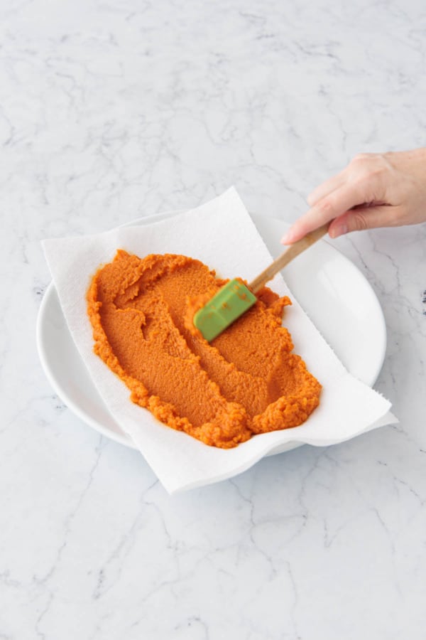 Spreading pumpkin puree on a paper towel lined plate.