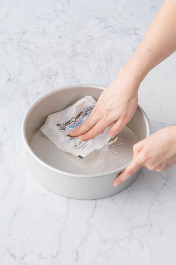 Buttering a 9-inch round deep cake pan with removable bottom.