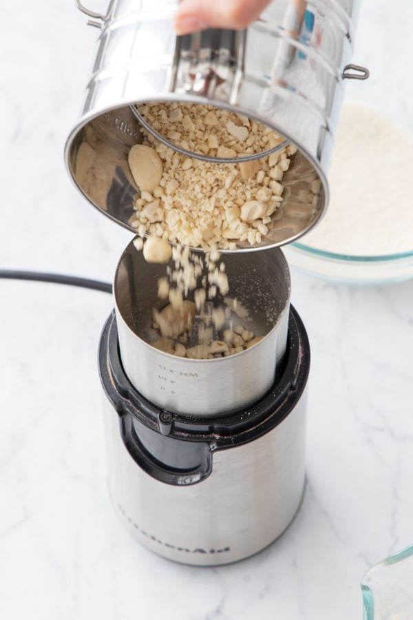 Pouring the bigger chunks of ground almond back into the coffee grinder.