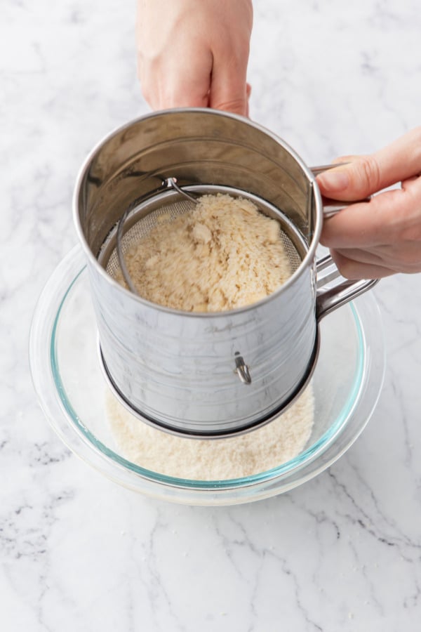 Sifting homemade almond flour to let only the finest particles go through.