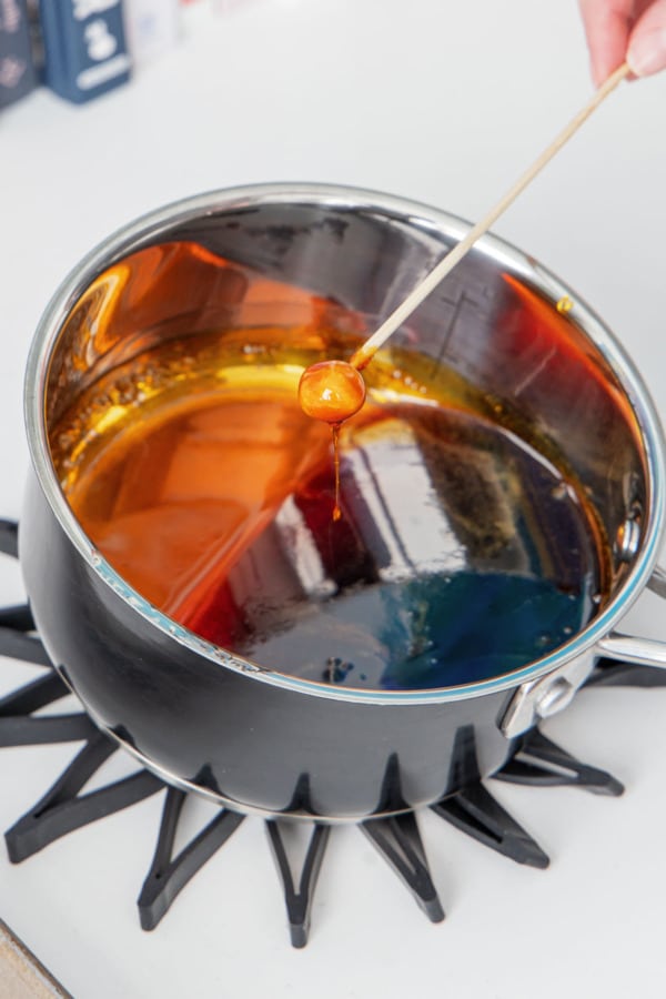 Dipping a whole hazelnut on a skewer into a saucepan with thick caramel.