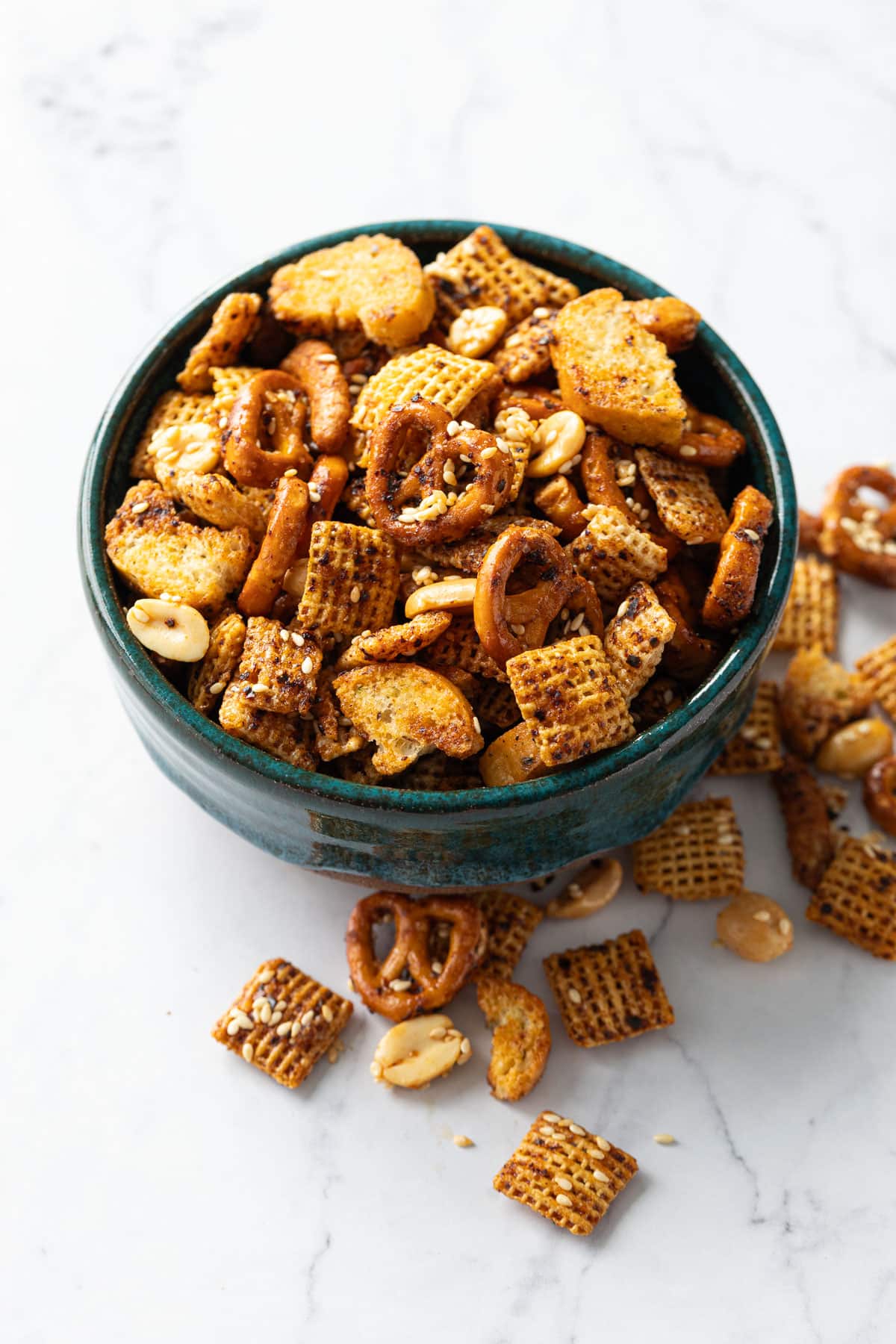 Teal ceramic bowls overflowing with homemade sweet & spicy sesame snack mix on marble background.