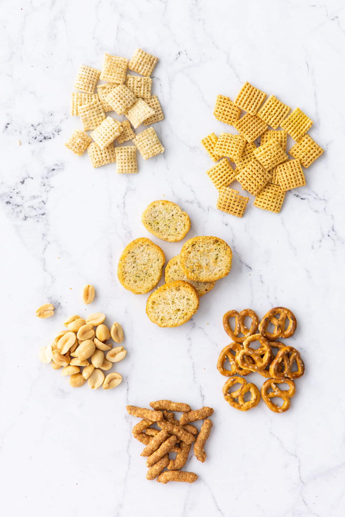 Flat lay on marble showing individual ingredients used in this snack mix recipe.