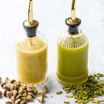 Side by side comparison of two bottles of Homemade Pistachio Syrup made with different kinds of pistachios (one is clearly greener than the other).