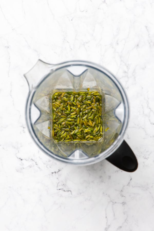 Top down view of blender canister with pistachios and sugar syrup before blending.