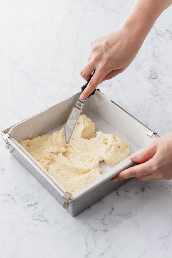 Spreading first layer of cake batter into a smooth layer using an offset spatula.