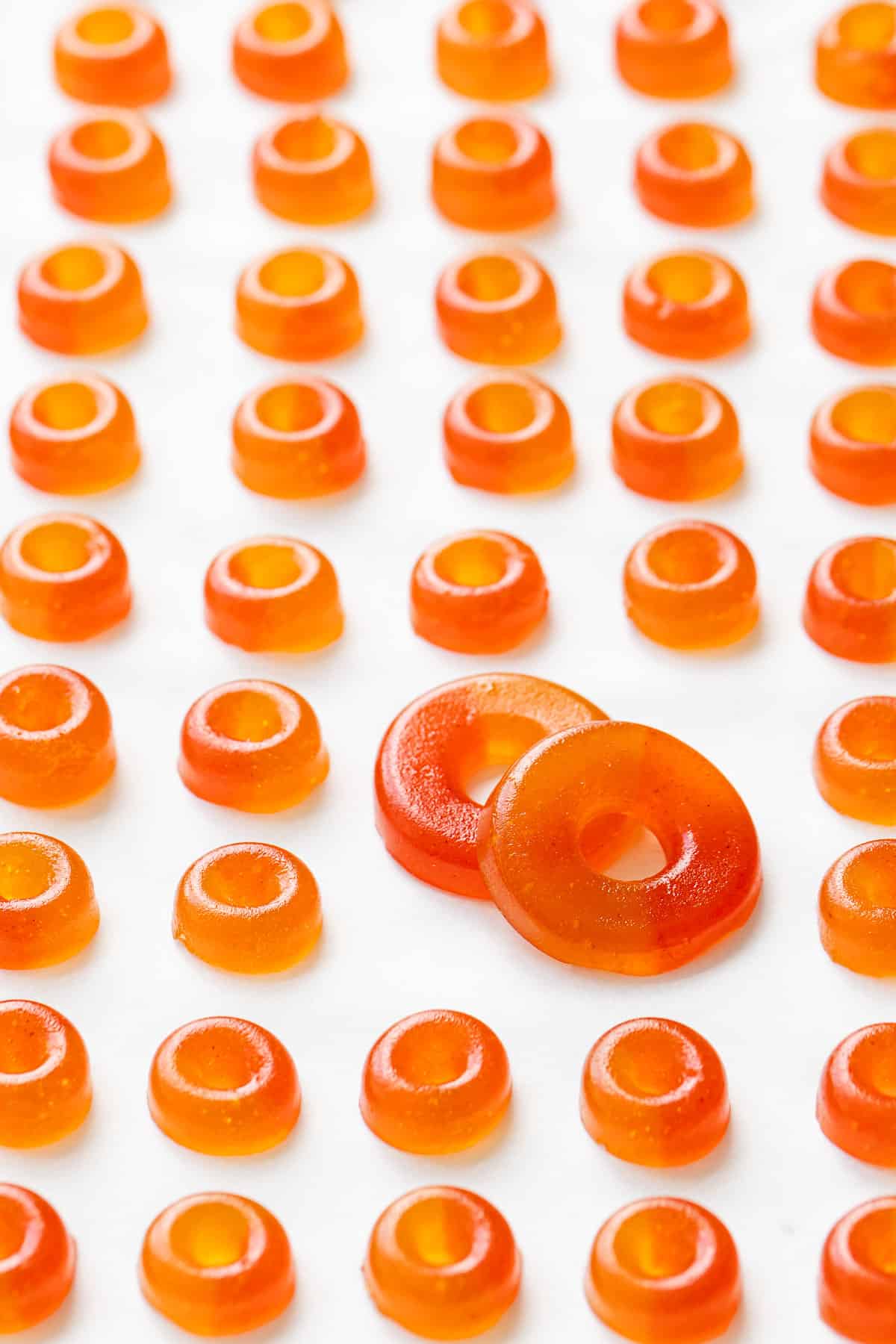 Rows of small Homemade Gummy Peach Rings in even rows, with two larger peach rings in the middle.