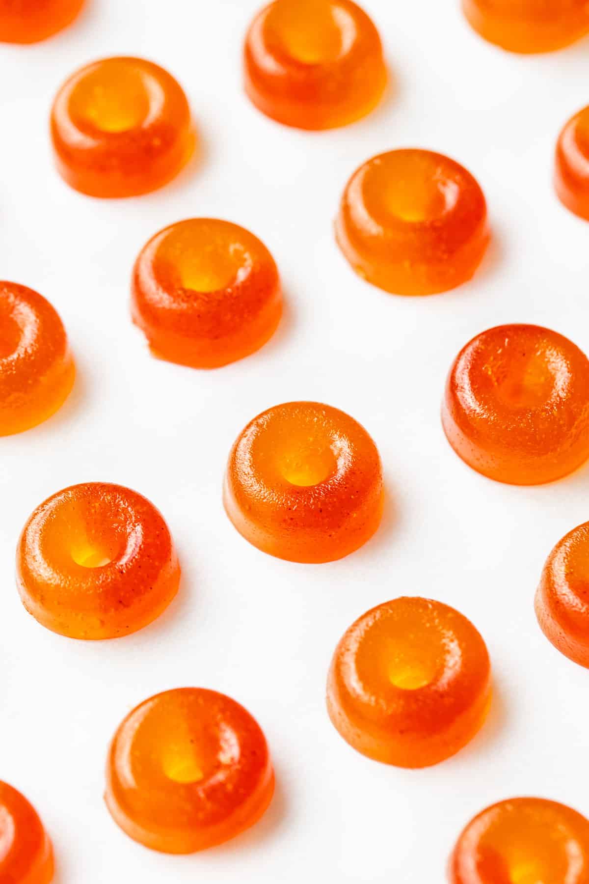 Close up shot of Homemade Gummy Peach Rings with two-toned orange and red color effect, on a parchment paper background.