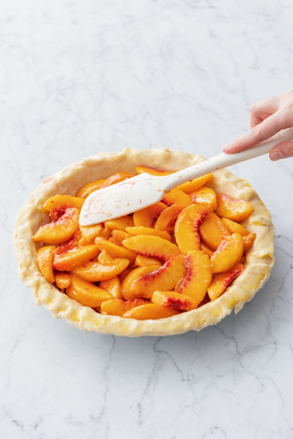 Smoothing top of peach filling with a silicone spatula.