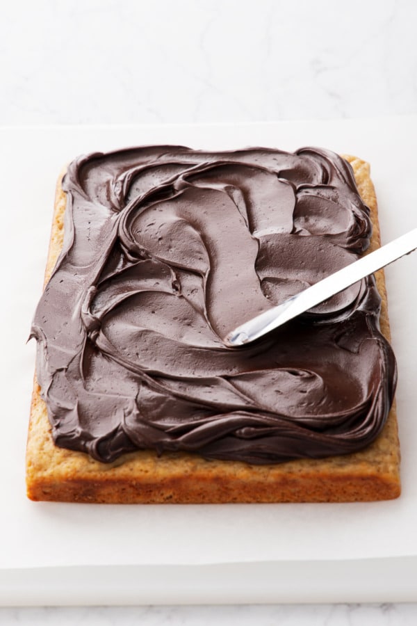 Offset spatula making shiny, swoopy swirls in the chocolate fudge frosting.