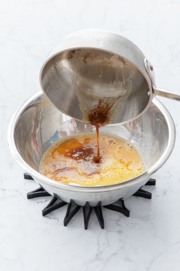 Pouring brown butter into a mixing bowl with granulated sugar.