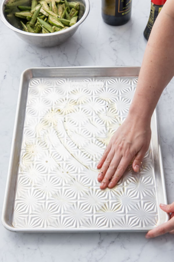 Spreading oil onto an unlined, aluminum baking sheet.
