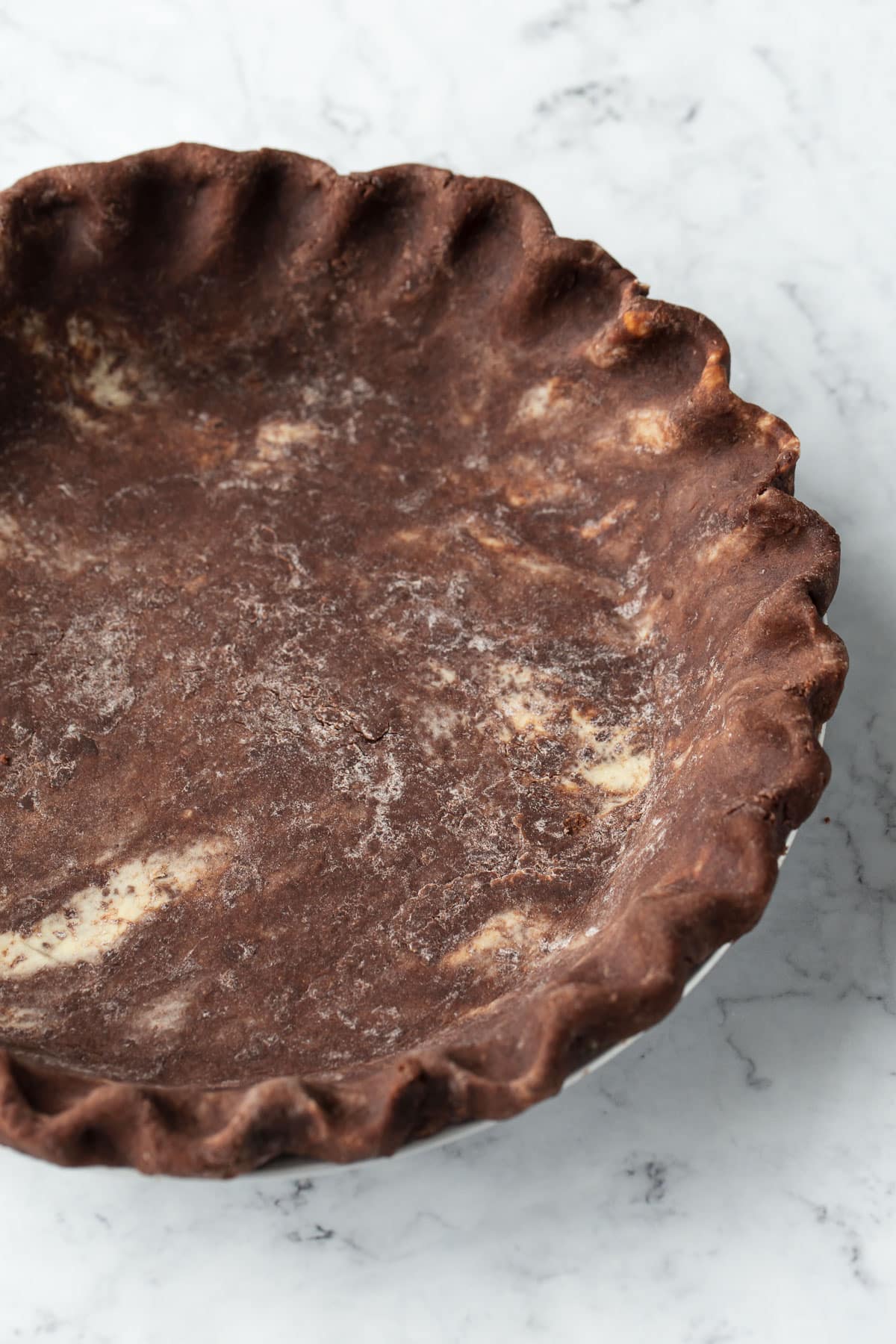 Closeup of the fluted edge of an unbaked chocolate pie crust.