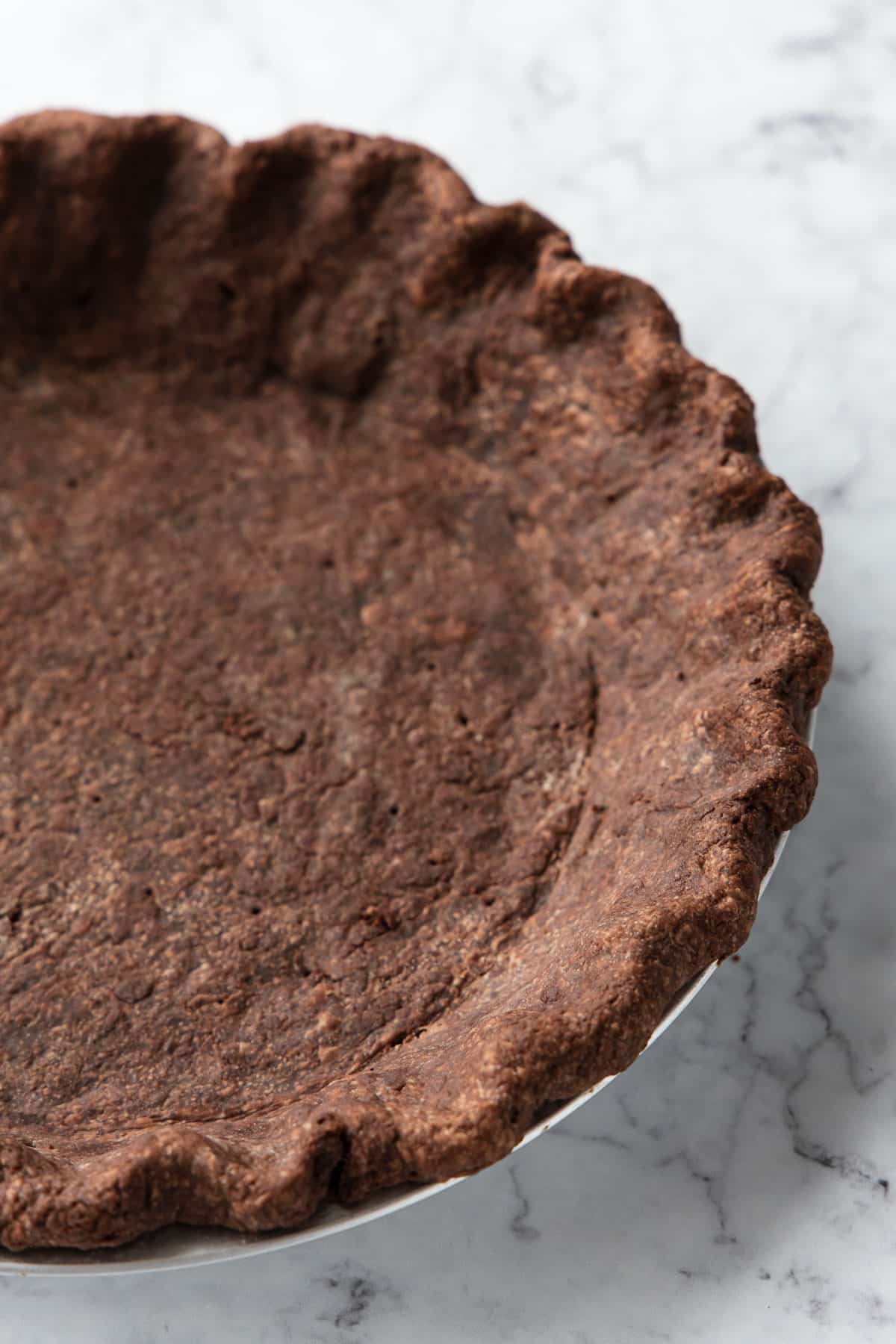 Closeup of the fluted edges of a chocolate pie crust after a full blind bake.