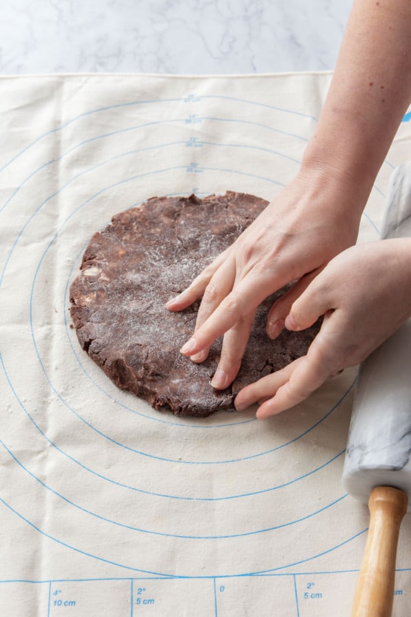 Pinching the sides together as you roll to prevent breaking.