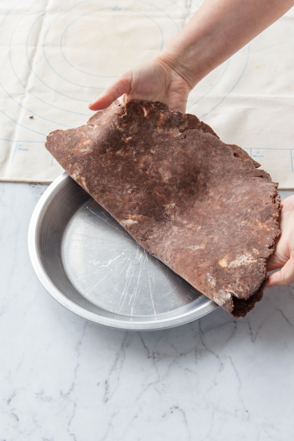 Folding pie dough in half and draping into a 9-inch metal pie pan.