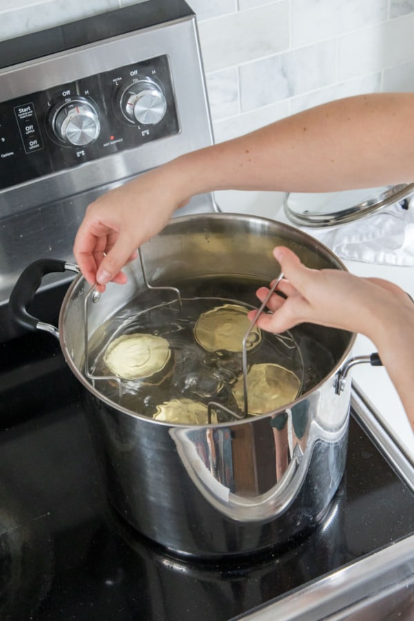 Lowering jam-filled jars into a canning pot filled with boiling water.