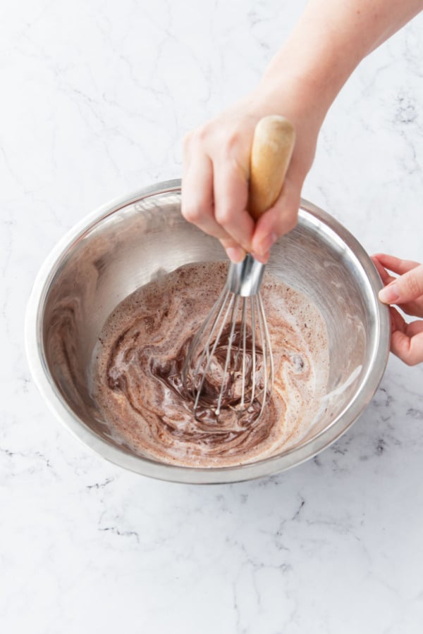 Whisking hot cream and chocolate until it starts to melt and emulsify.