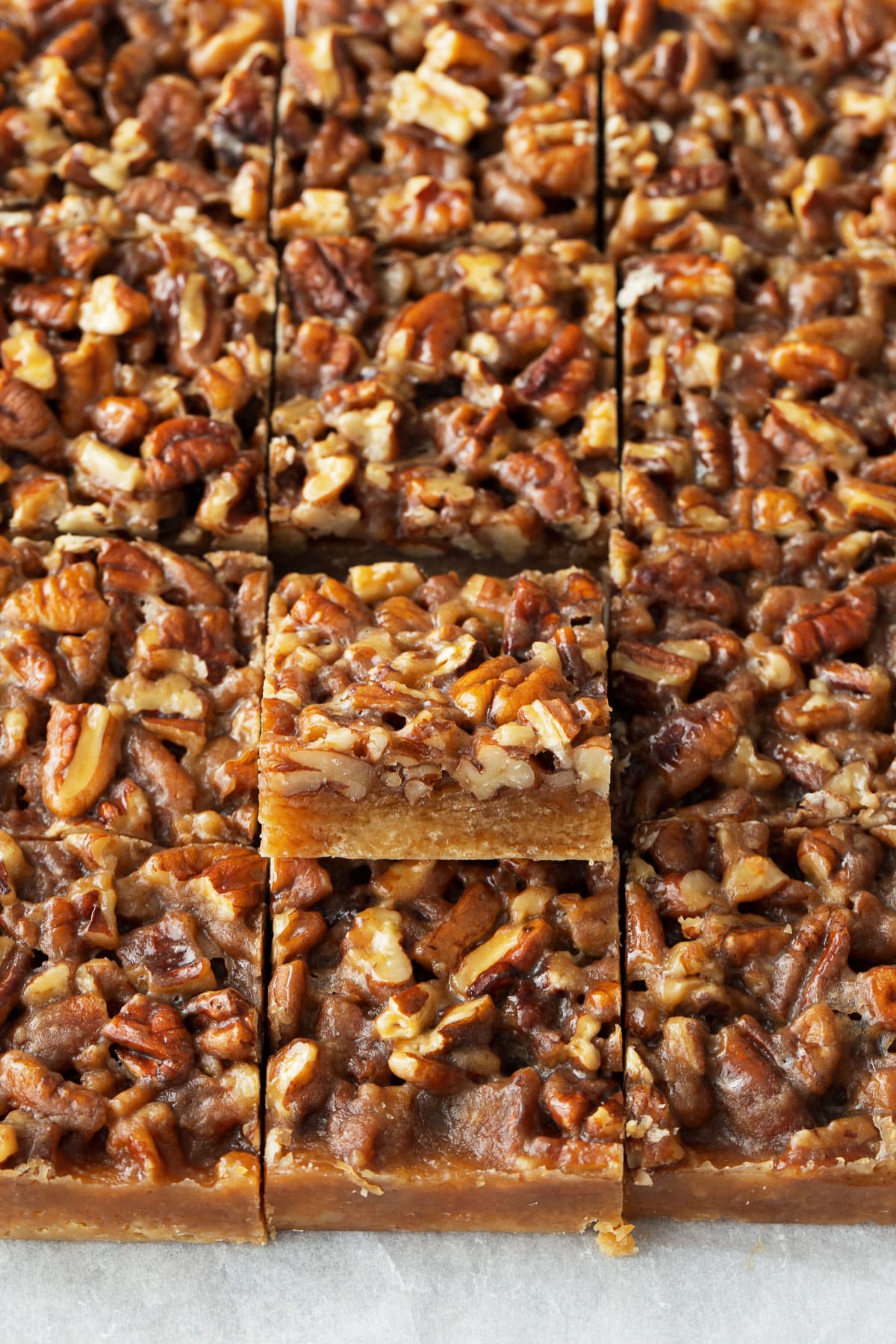 Pecan Pie Shortbread Cookie Bars cut into squares, one tilted upwards to show the layers.