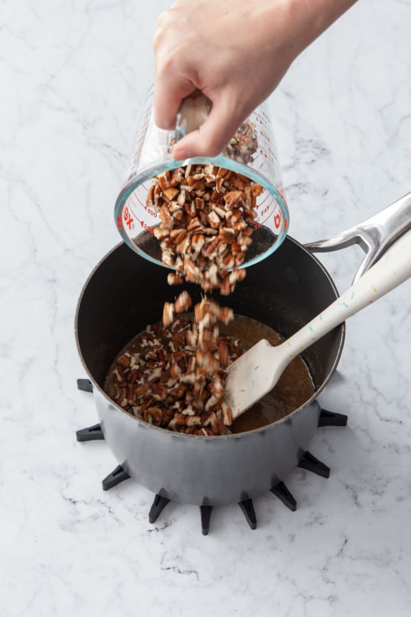 Adding chopped pecans to the sugar syrup filling.