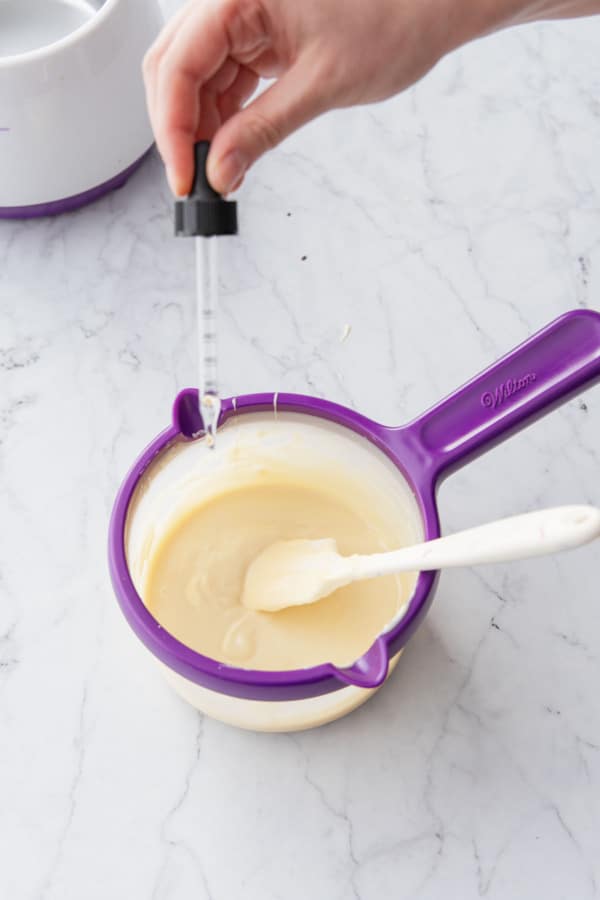 Adding drops of peppermint flavoring oil to the tempered white chocolate.