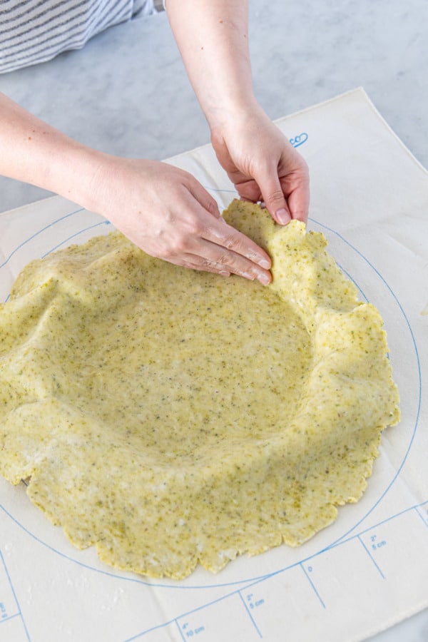 Easing the rolled tart dough into the tart pan without stretching.